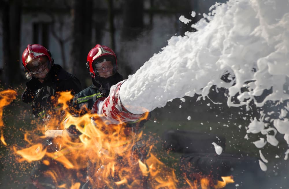 firefighters shooting foam to calm fire