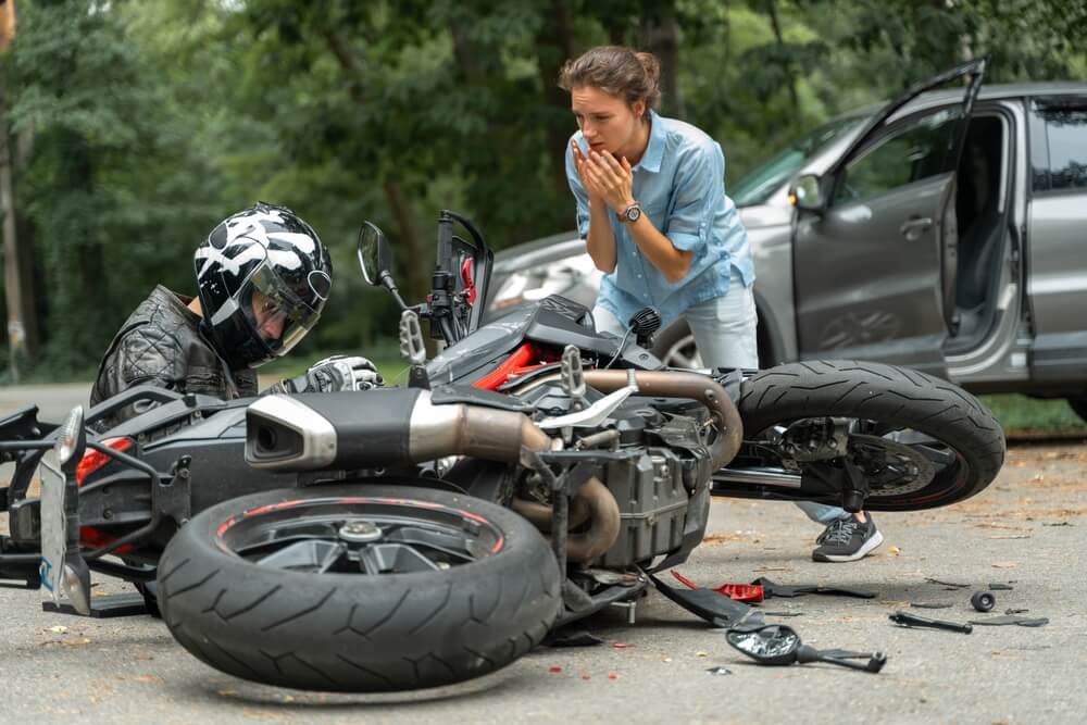 Motorcycle accident in Greensboro with injured rider and concerned driver at the scene
